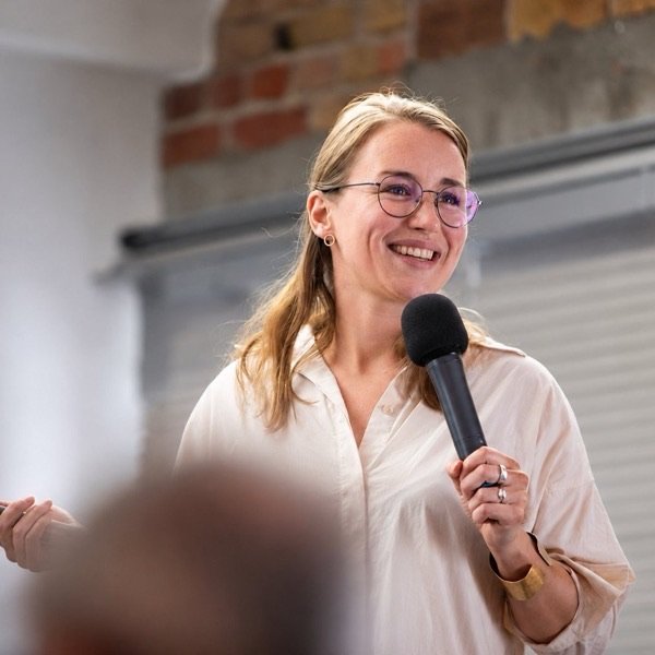 Lia Weitz speaking into a microphone in front of a group