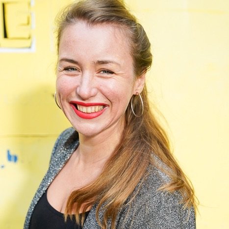Lia Weitz laughing in front of a yellow wall